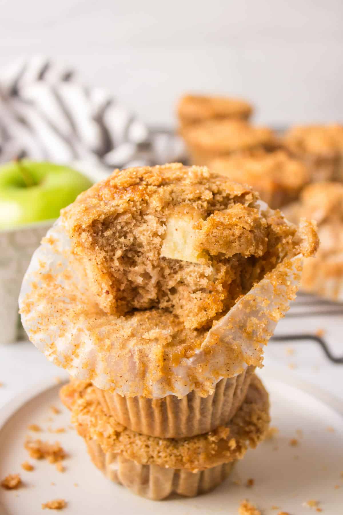An apple muffin with bite out of it on top of two other muffins.