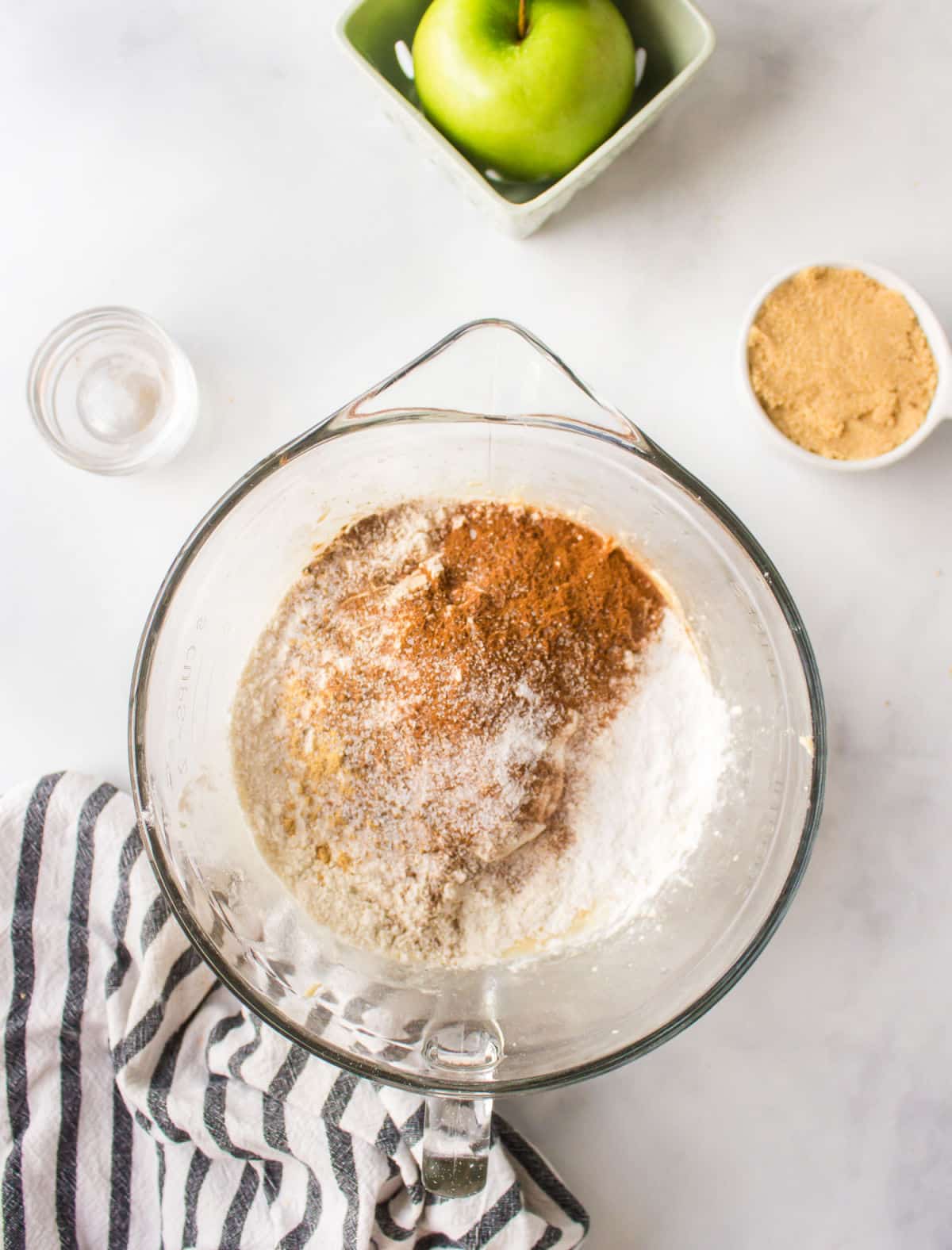 Dry ingredients on top of wet batter in a glass mixing bowl.