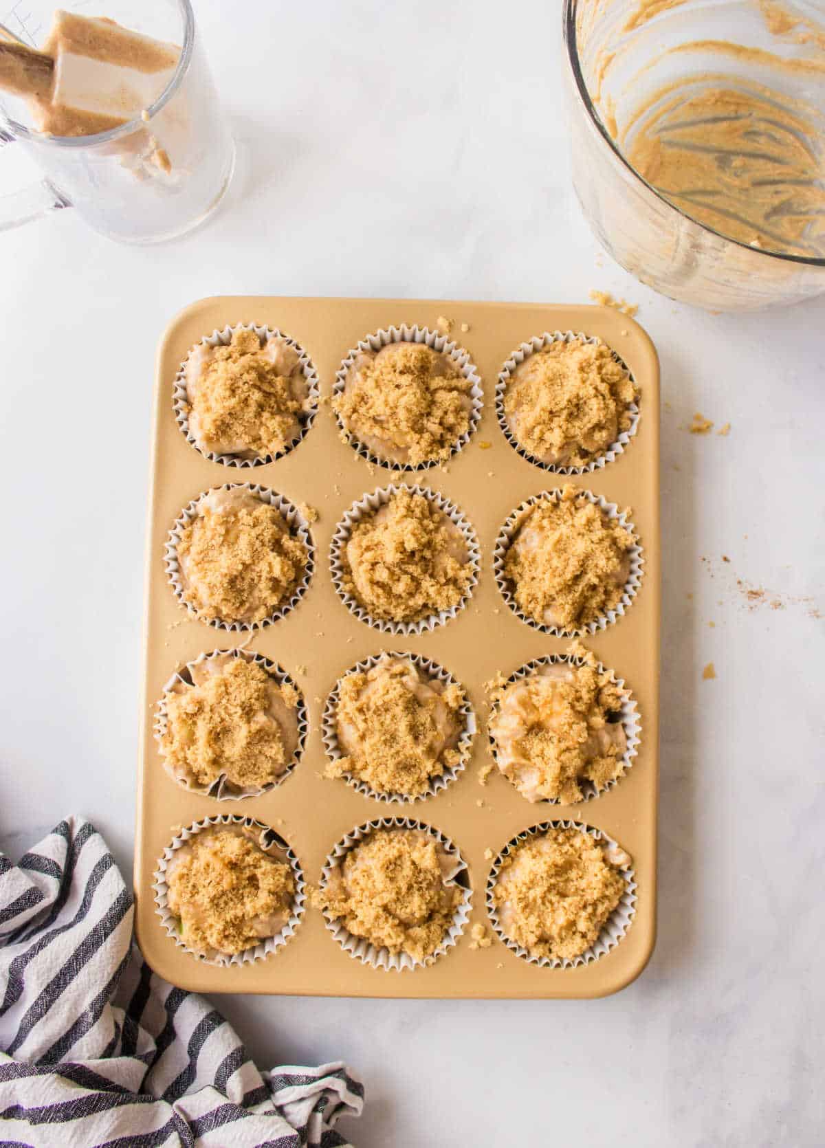 Apple muffin batter in a muffin tin.