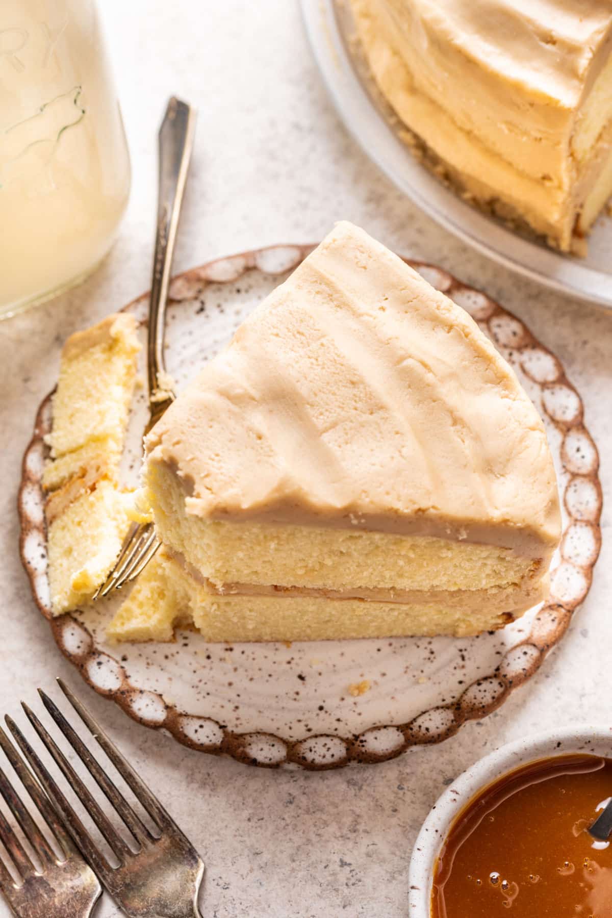 A fork cutting a bite from a slice of caramel cake.