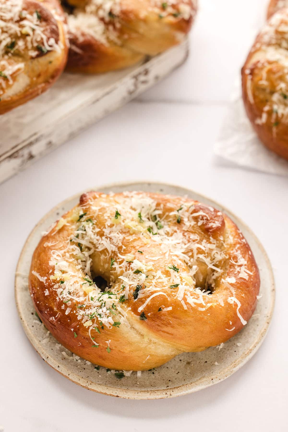 A garlic parmesan pretzel on a white plate.