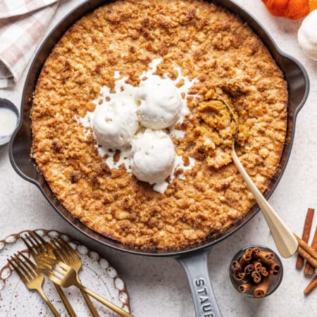A gold fork in a skillet of pumpkin crisp.
