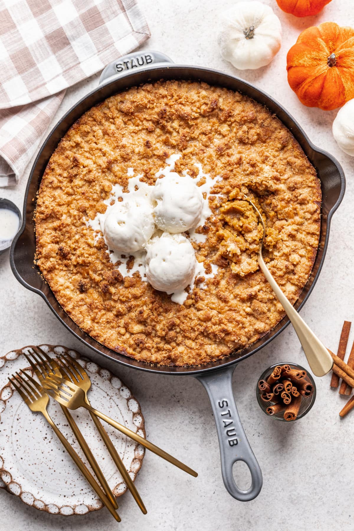 A gold spoon in a skillet of pumpkin crisp.
