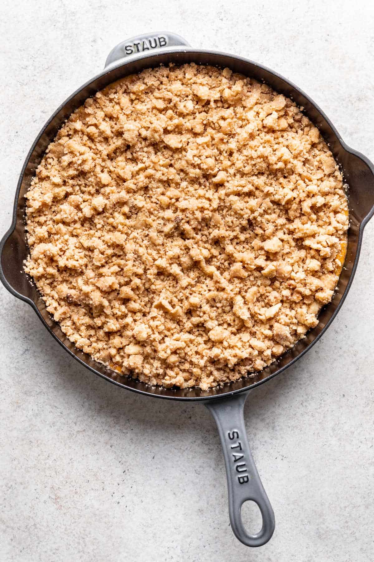 Crumble topping on pumpkin crisp filling in a skillet.