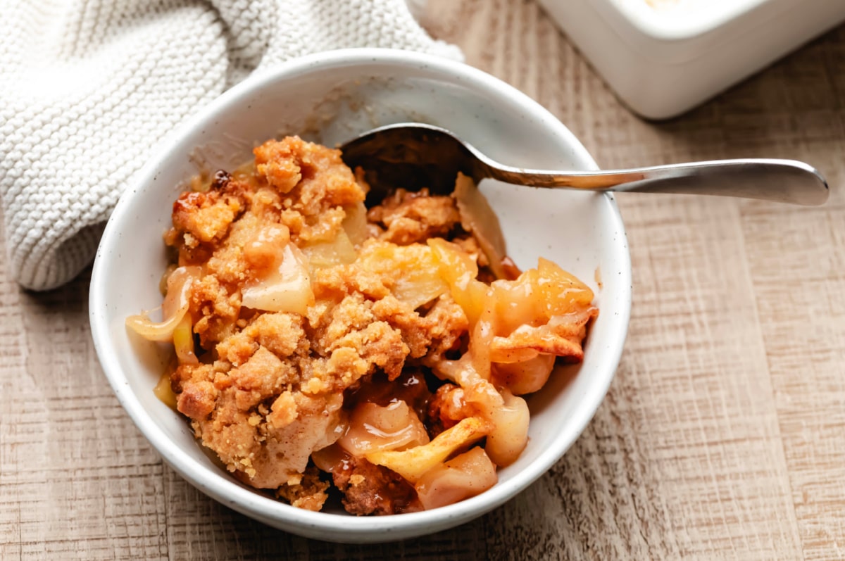 A silver spoon in a bowl of apple crumble.