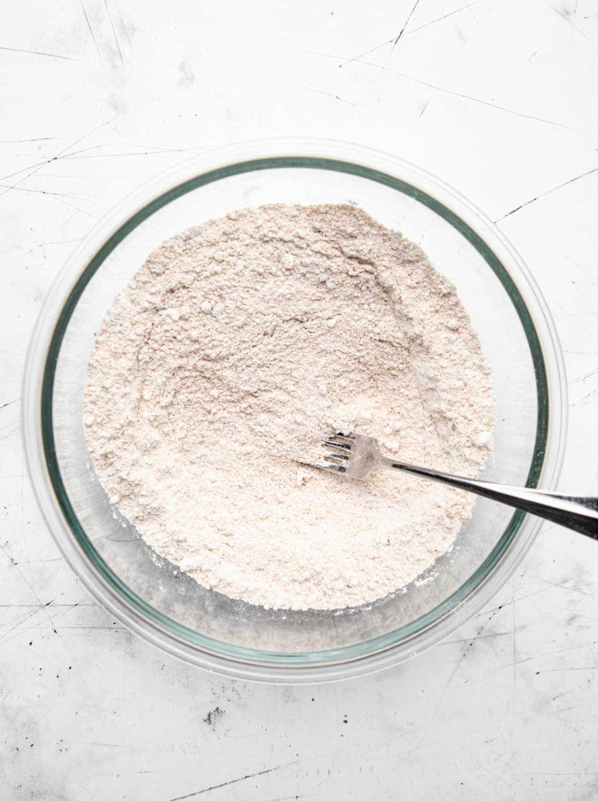 Dry ingredients for crumble topping in a glass mixing bowl.