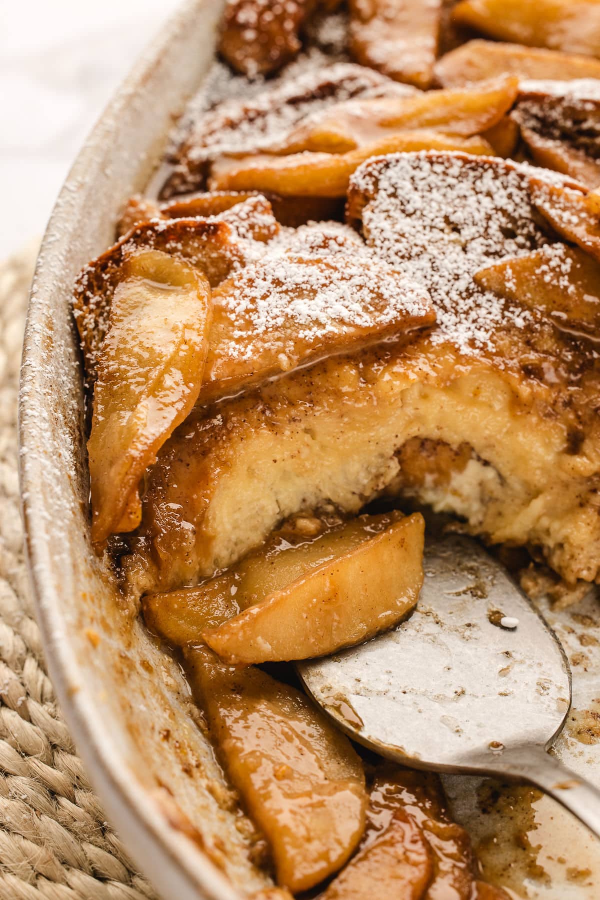 A silver spatula getting a piece of apple baked French toast.
