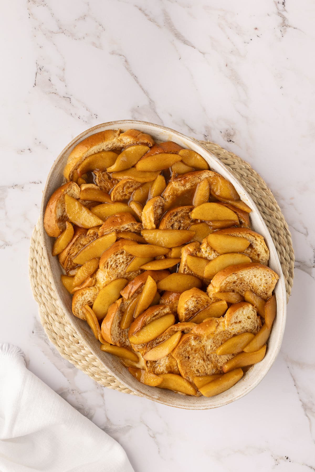 Apple sauce spooned over slices of brioche in a baking pan.