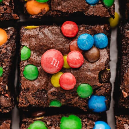 A row of M&M brownies on parchment paper.