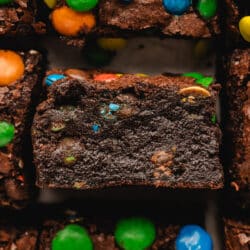 A row of cut M&M brownies with the middle brownie on its side.