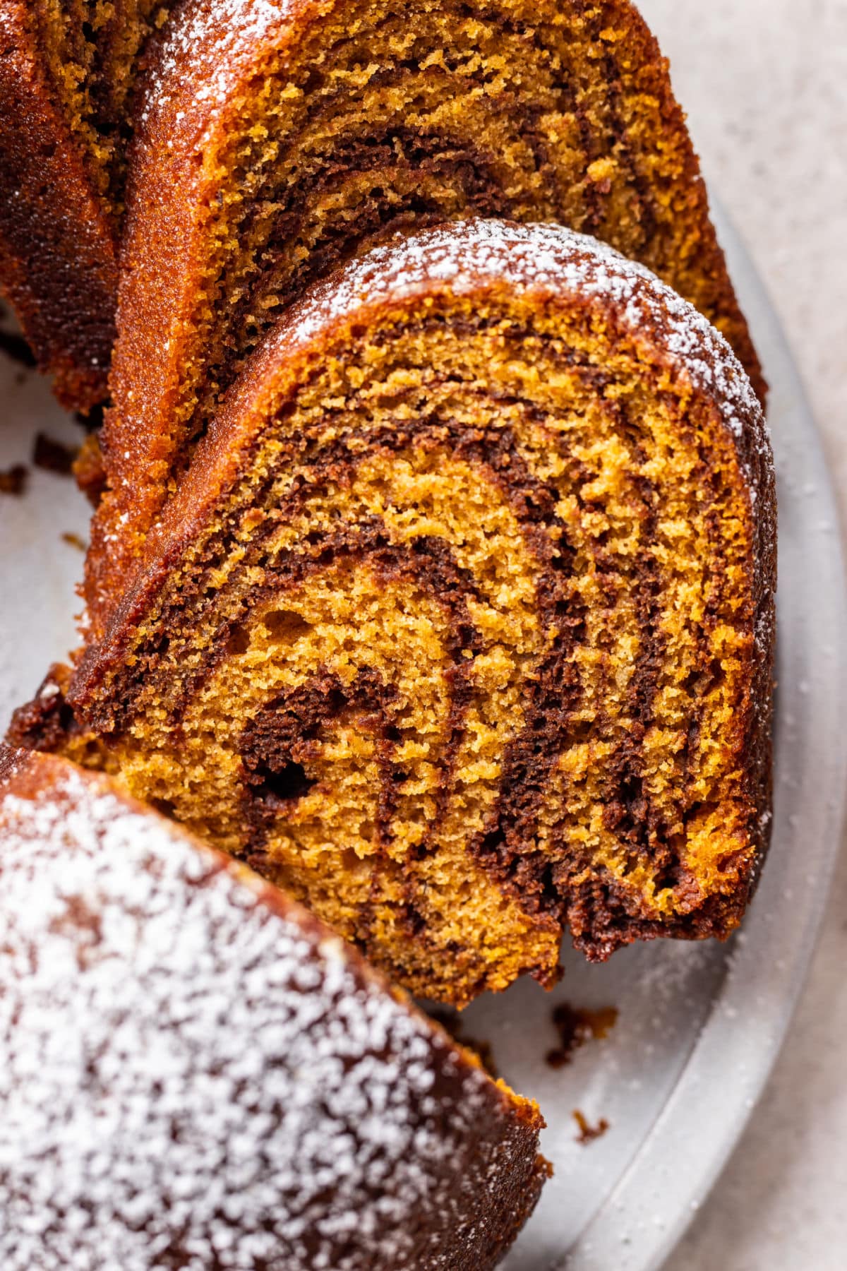 Close up slices of pumpkin marble cake on a white platter.