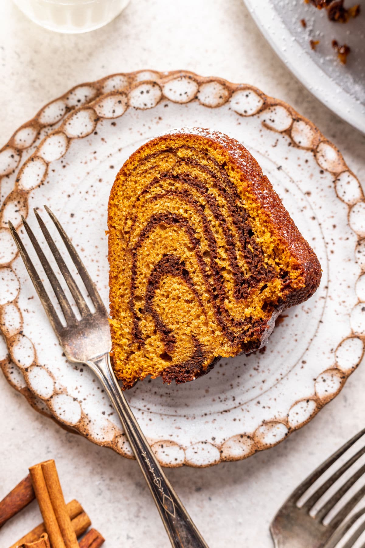 A slice of pumpkin marble cake and a silver fork on a plate.