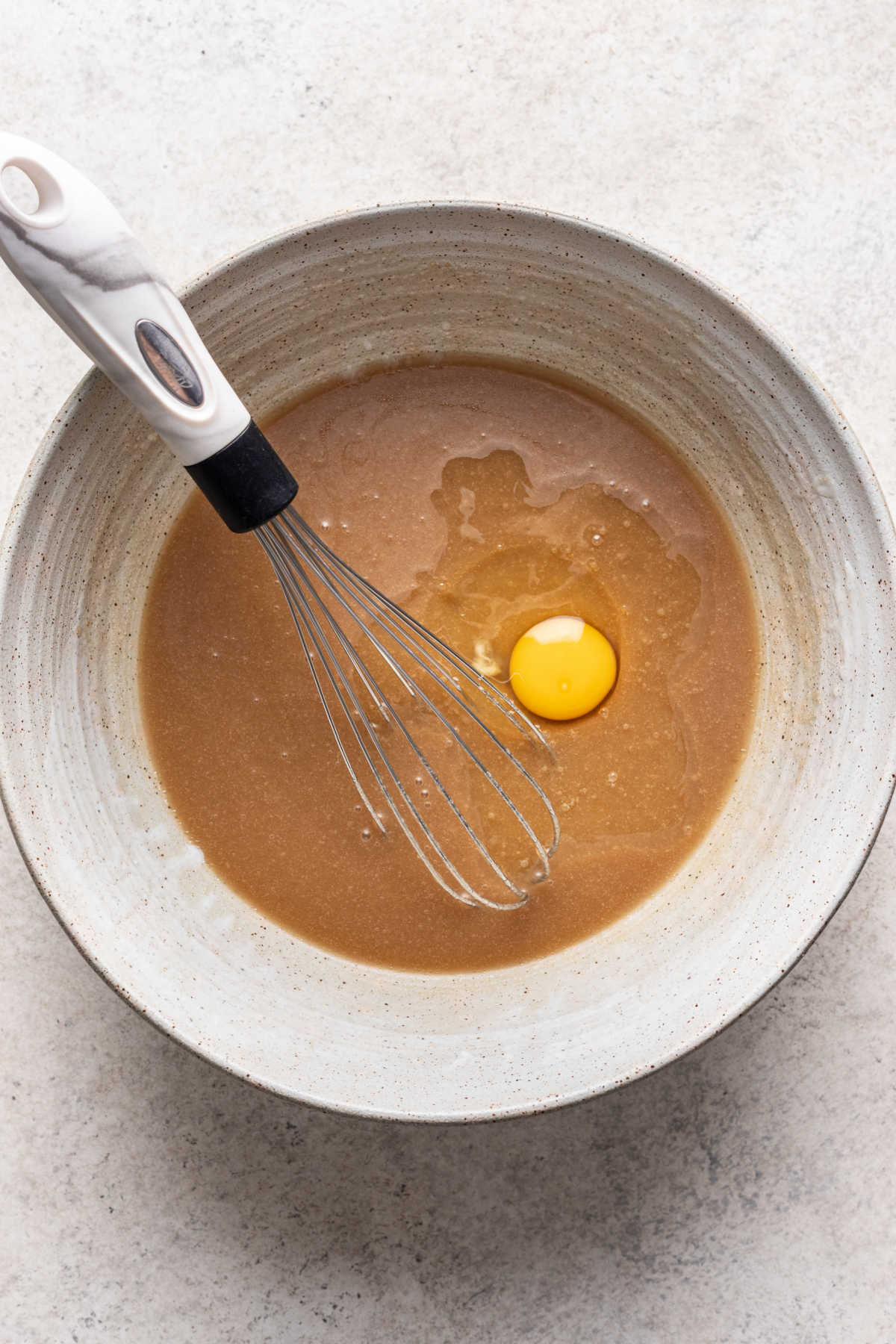 Eggs being whisked into oil and sugar mixture.