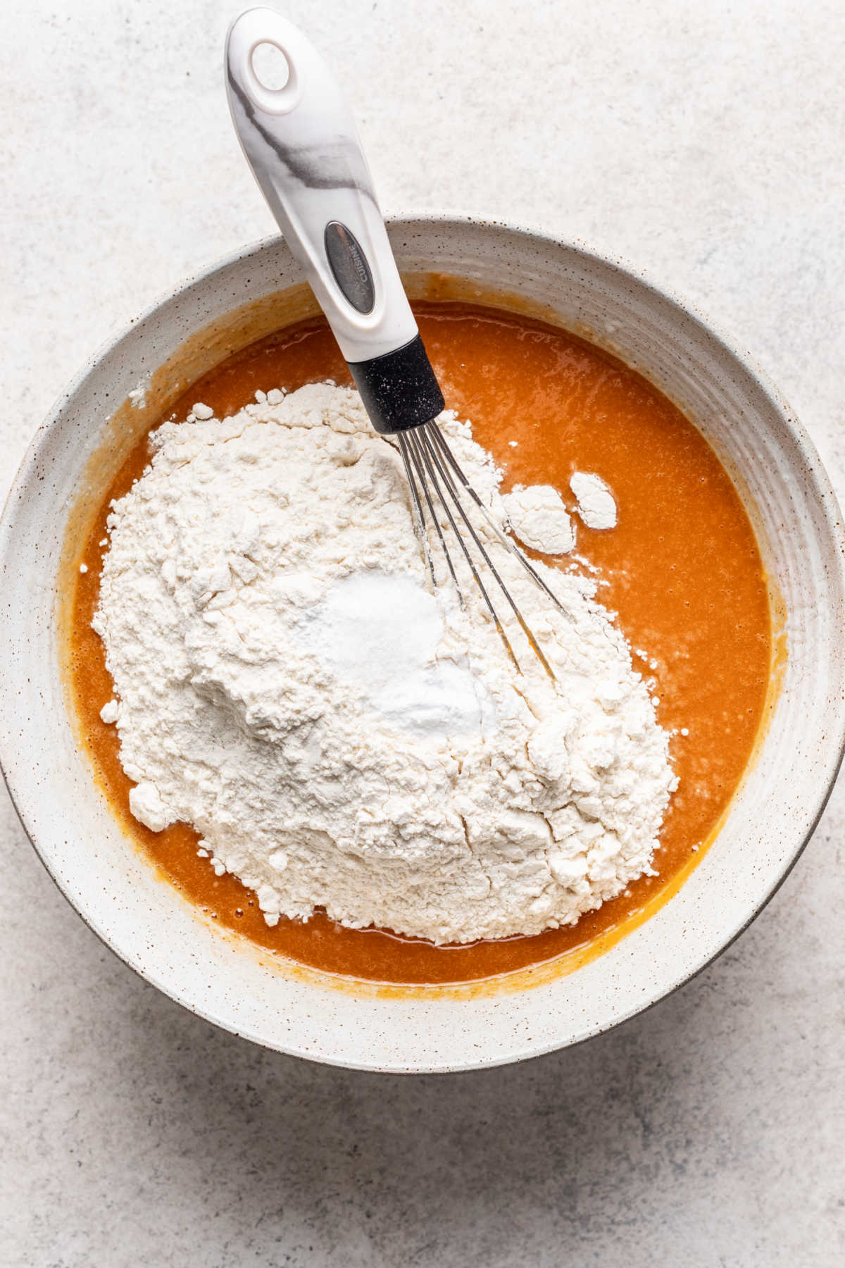 Dry ingredients on wet ingredients for pumpkin marble cake.