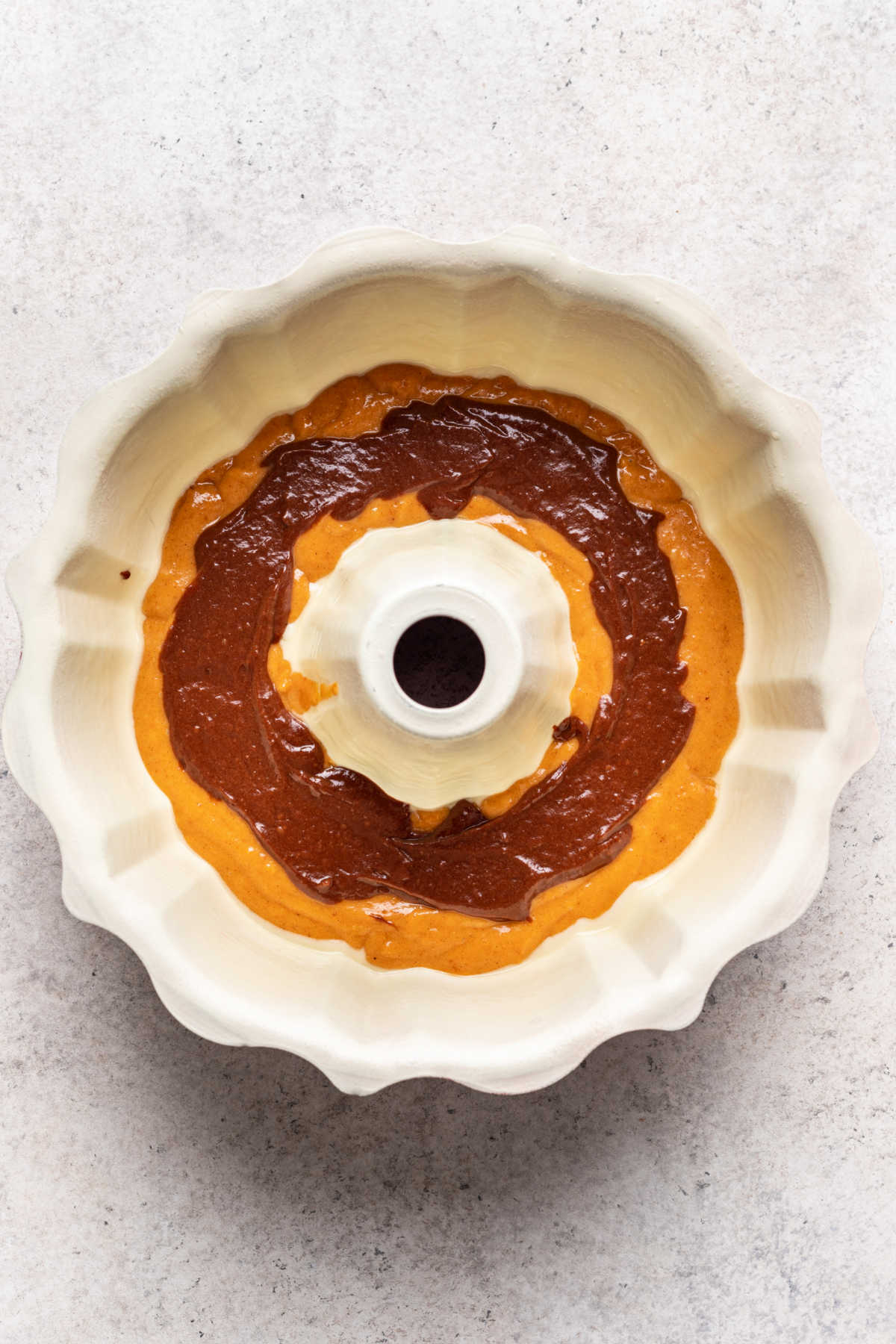 Chocolate batter on top of pumpkin batter in a bundt pan.