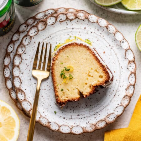 A slice of 7 up pound cake on a plate with a gold fork.
