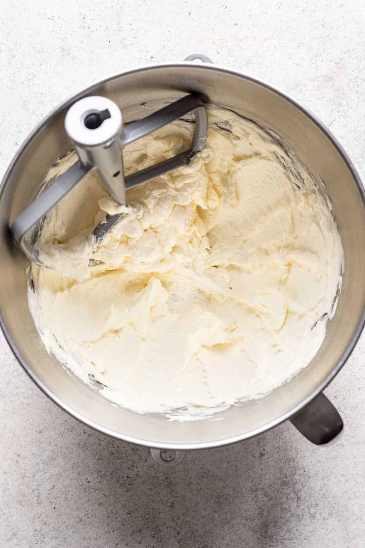 Creamed butter, cream cheese, and sugar in a silver mixing bowl.