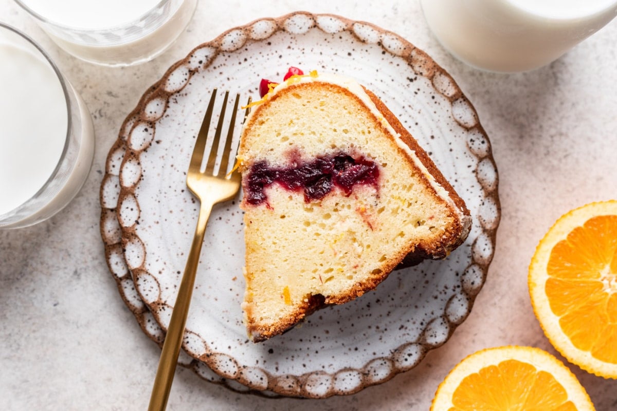 Cranberry Orange Pound Cake Recipe A slice of cranberry orange pound cake with a gold fork on a plate.