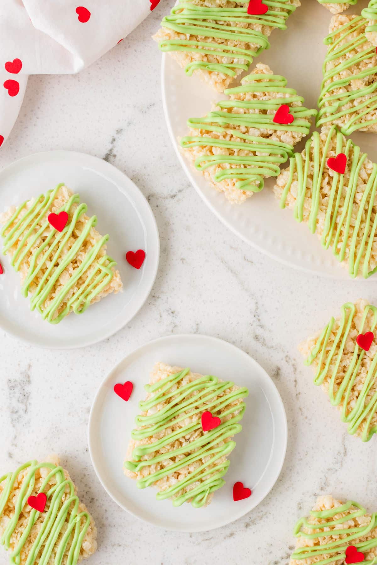 Plates of Grinch Rice Krispies treats next to a platter of treats.