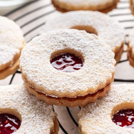 Linzer cookies overlapping on a black wire cooling rack.