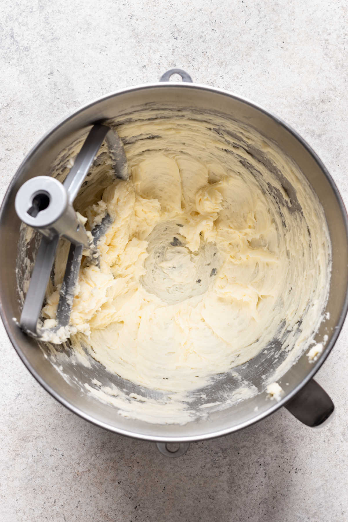 Butter and powdered sugar beaten together in a silver mixing bowl.