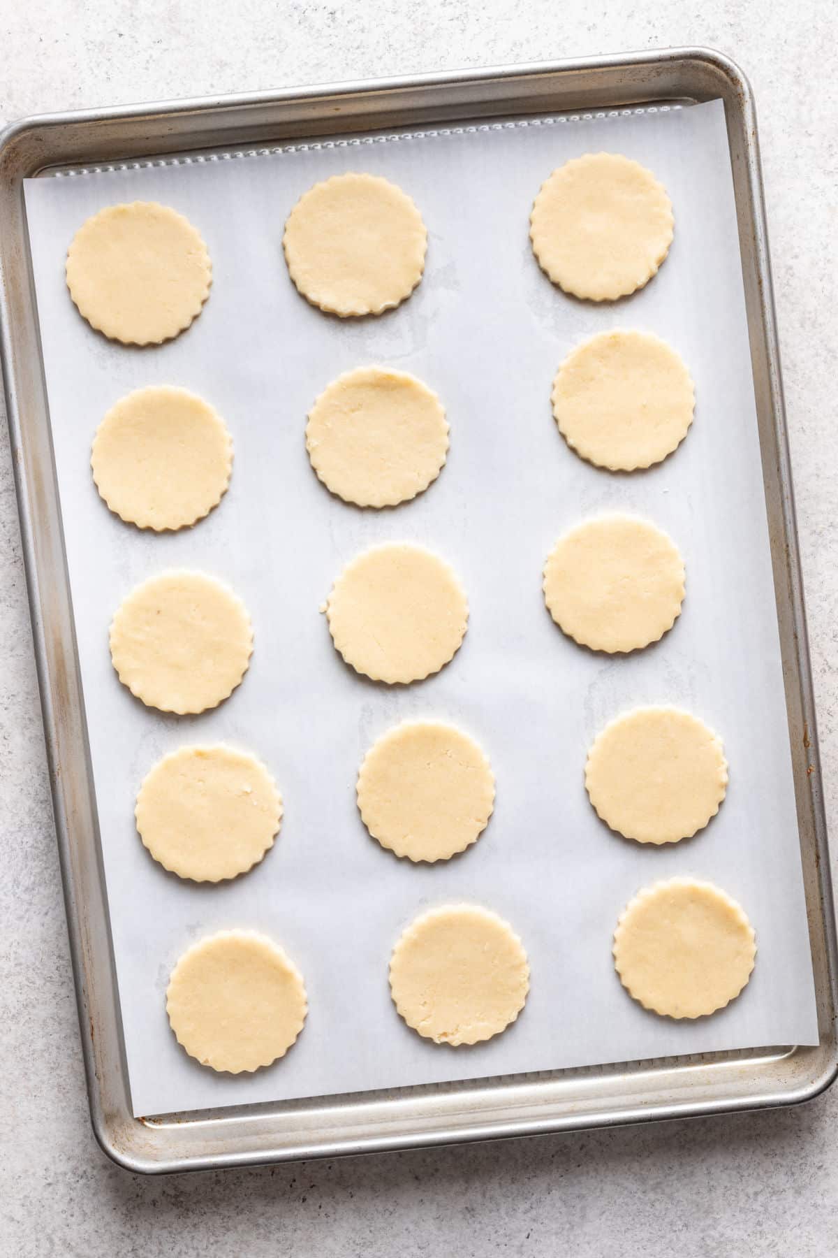 Linzer cookie dough circles on a parchment lined baking sheet.