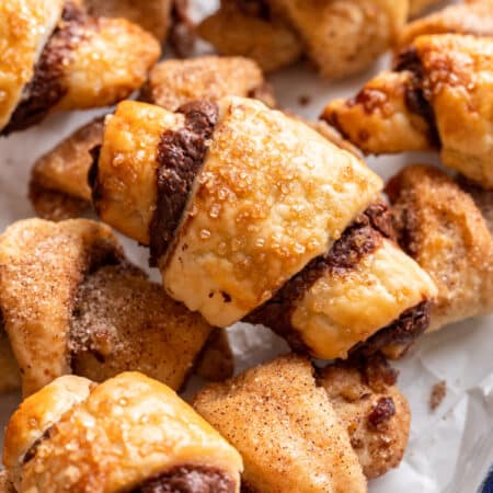 Nutella rugelach stacked on top of each other in a parchment lined pan.