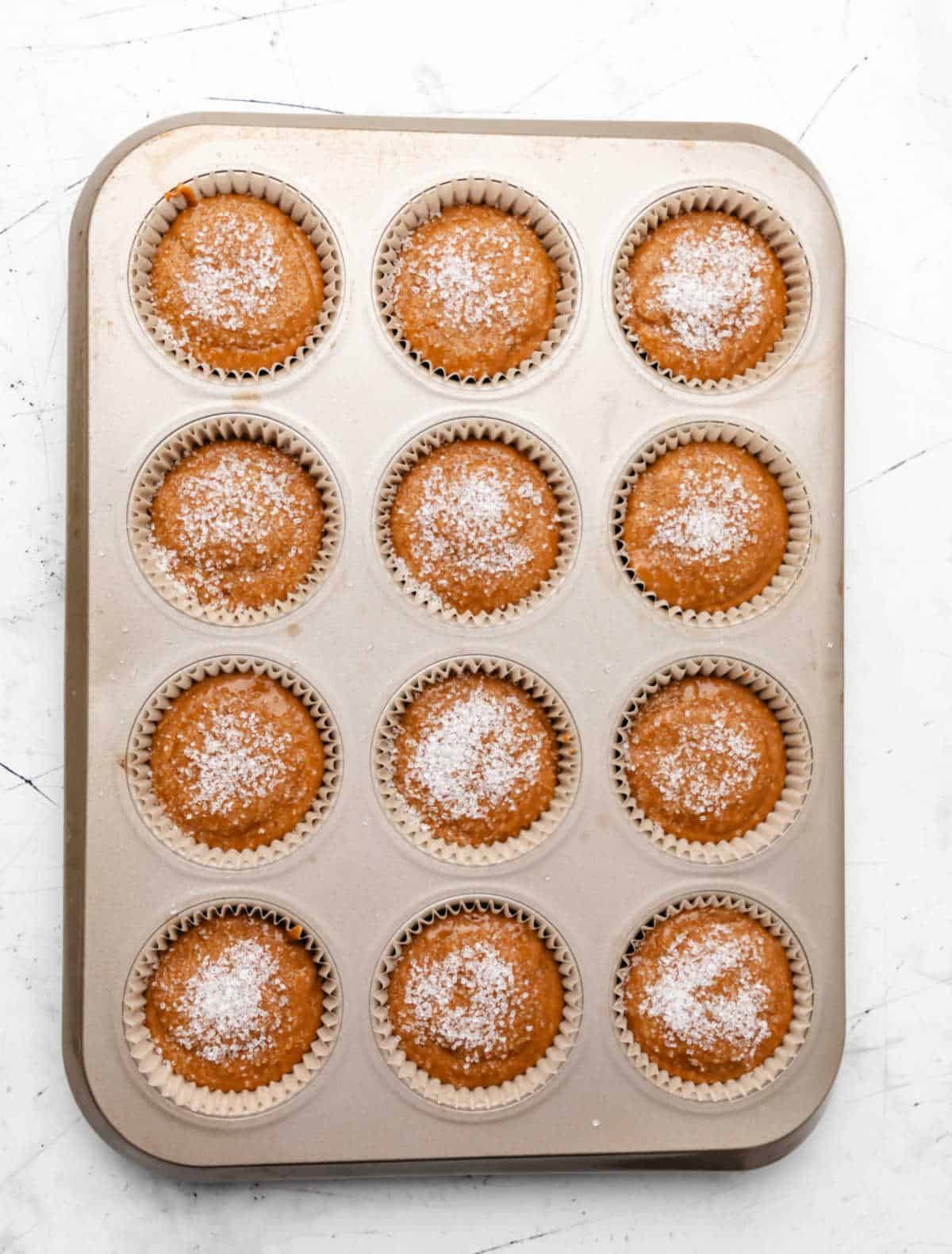 Sparkling sugar sprinkled over gingerbread muffin batter.