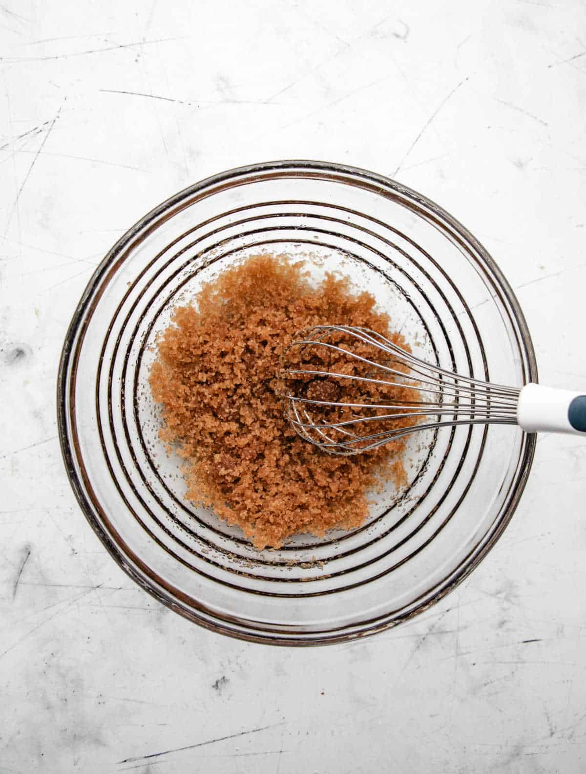 Gingerbread Muffin Recipe Oil and sugar whisked together in a glass mixing bowl.