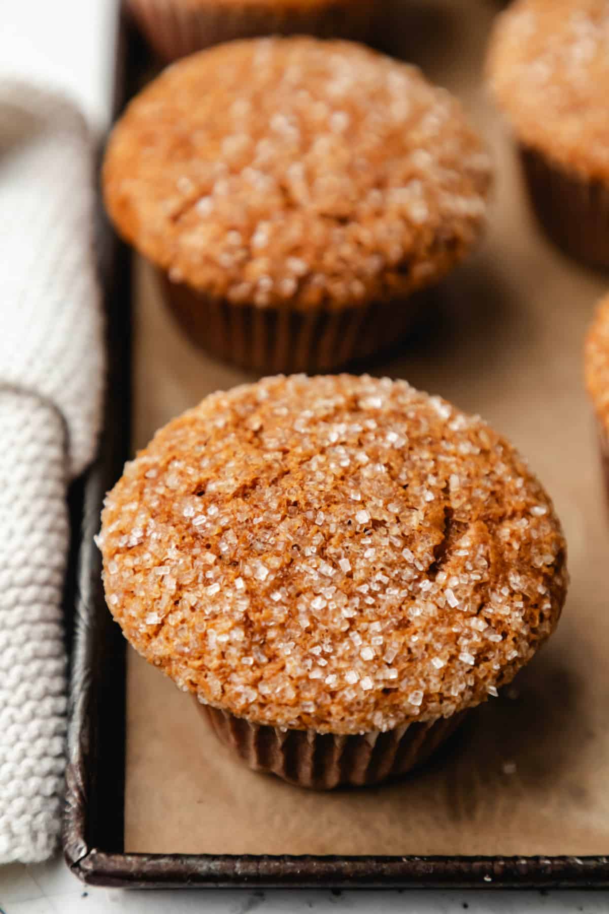 Gingerbread muffins on a brown parchment lined baking sheet.