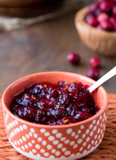 An orange polka dot dish with maple cranberry sauce in it.