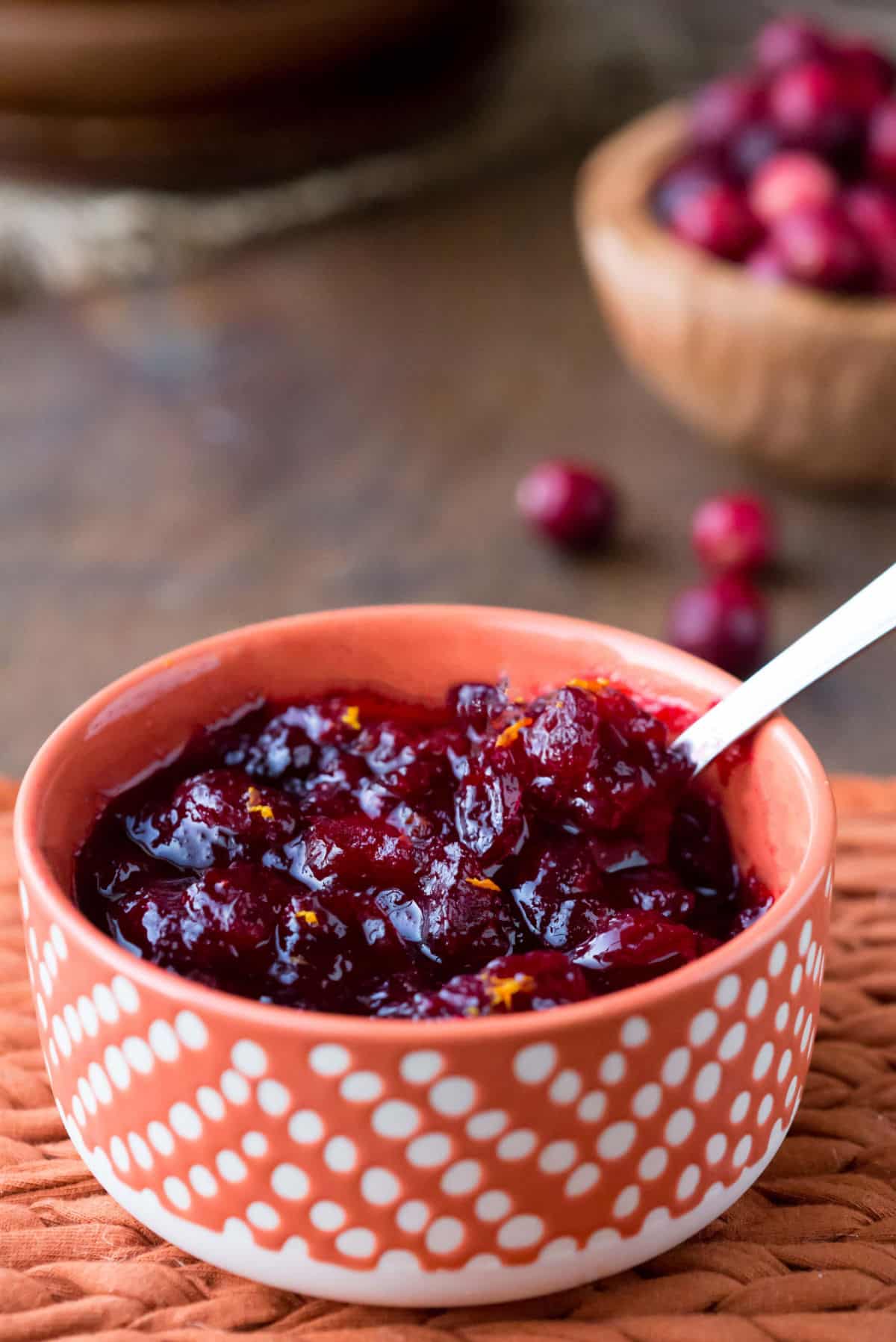 An orange polka dot dish with maple cranberry sauce in it.