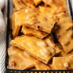 Microwave peanut brittle in a black metal bin.