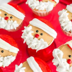 Rows of Santa cupcakes on a red plate.