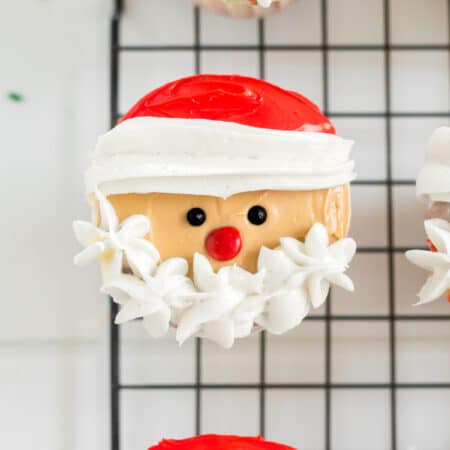 A row of Santa cupcakes on a wire cooling rack.