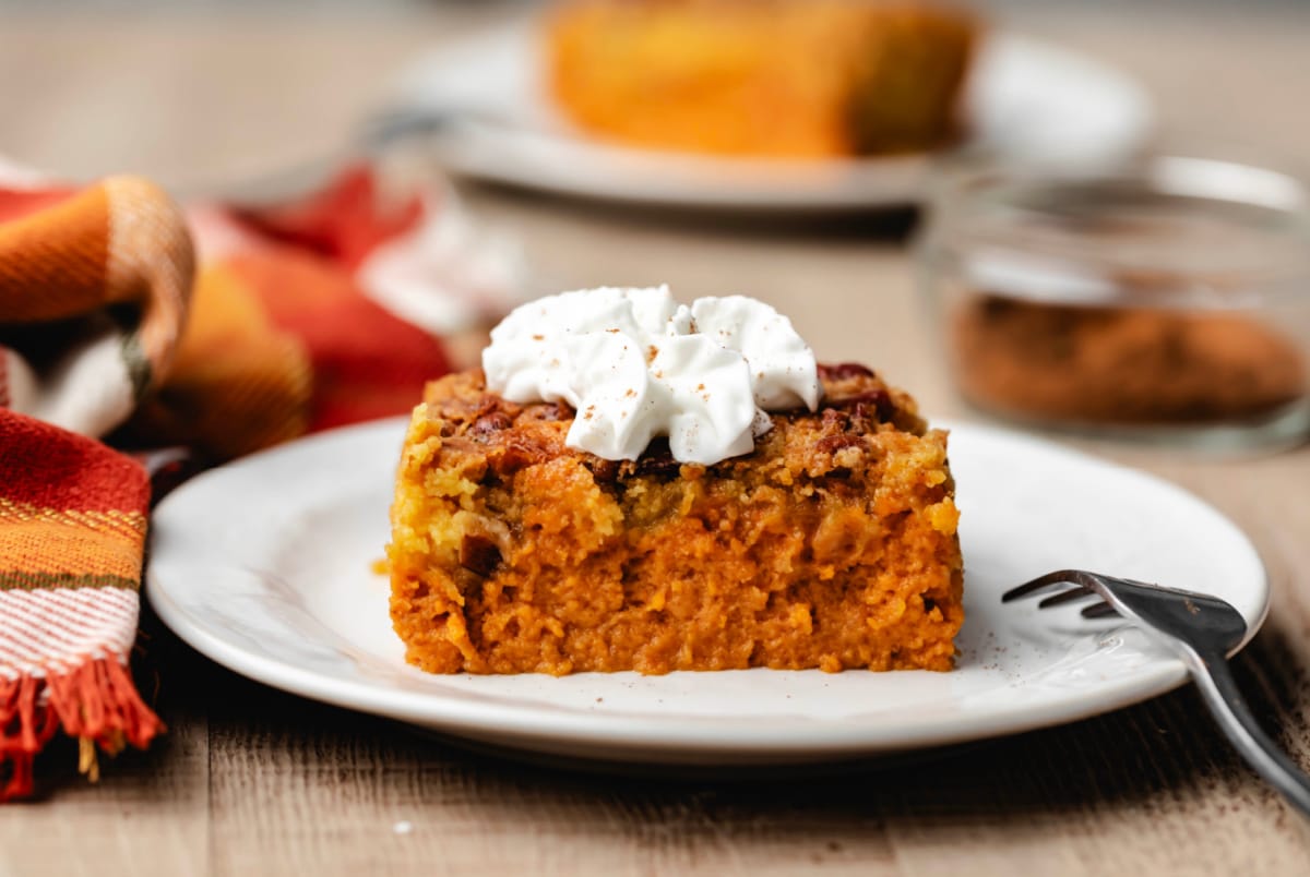 A slice of pumpkin pie cake topped with whipped cream.