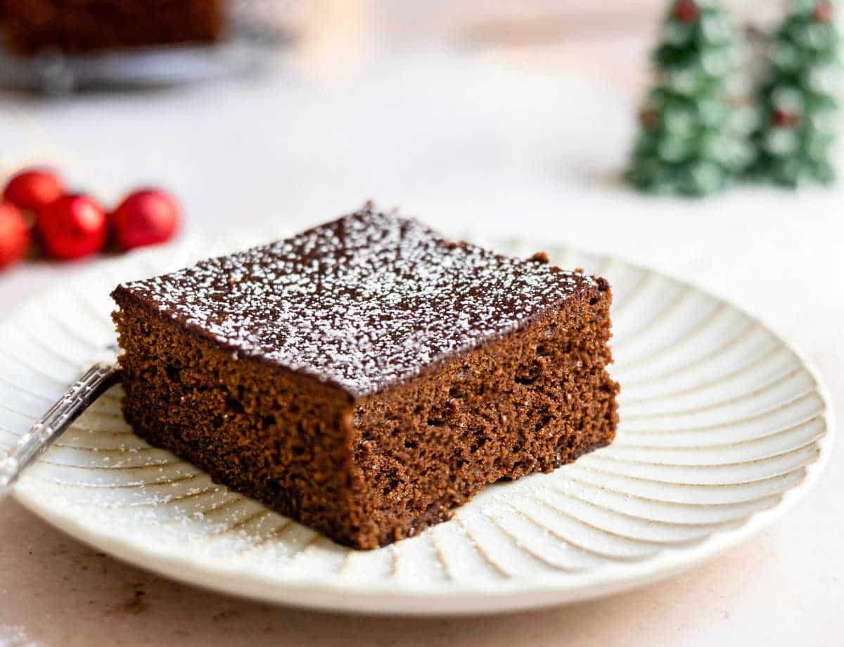 Gingerbread Piece of gingerbread on a white plate next to Christmas decorations.