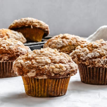 Four banana crumb muffins next to the pan.