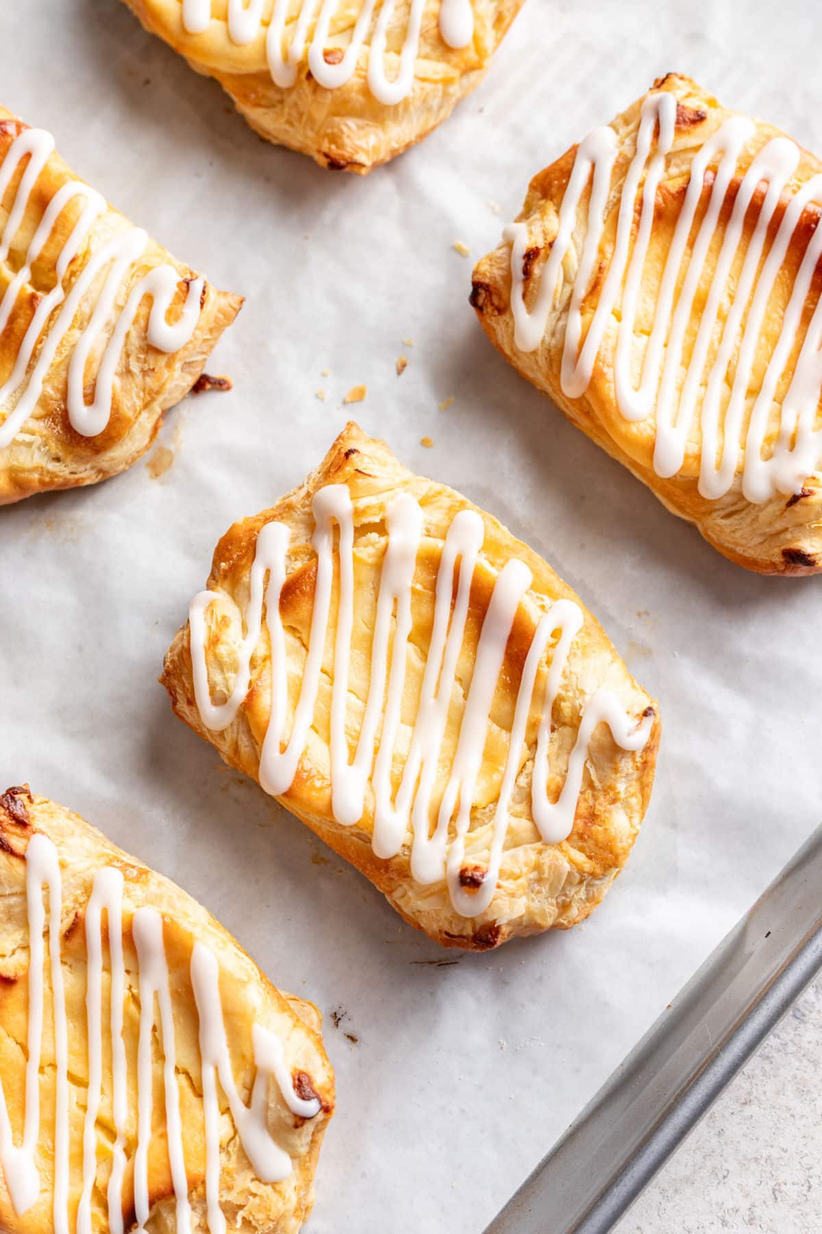 Iced cheese Danishes on a baking sheet.