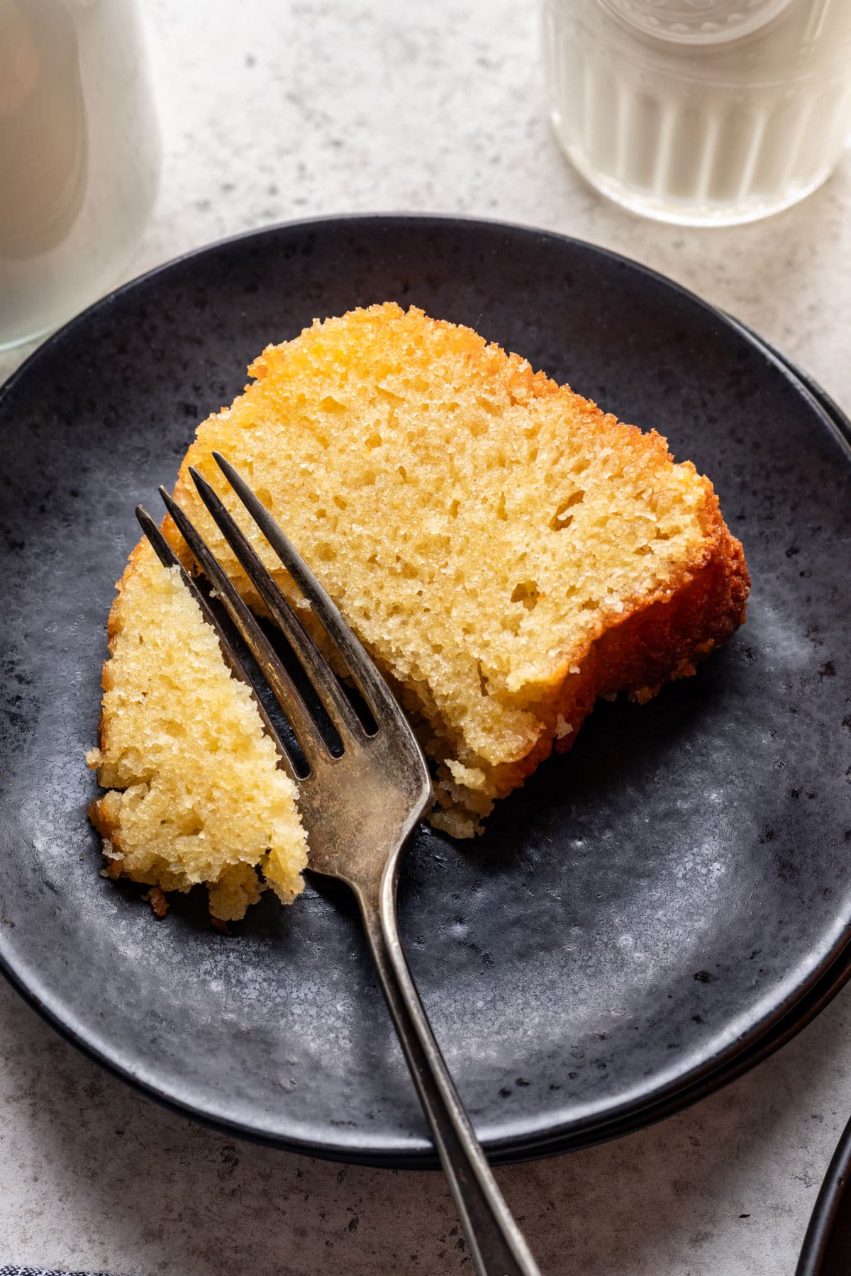 Kentucky Butter Cake Recipe A fork taking a bite of Kentucky butter cake on a black plate.