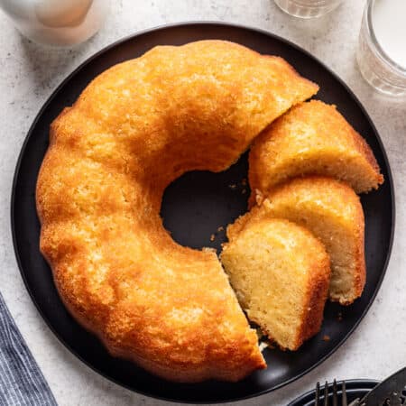 Kentucky butter cake on a black plate next to glasses of milk.