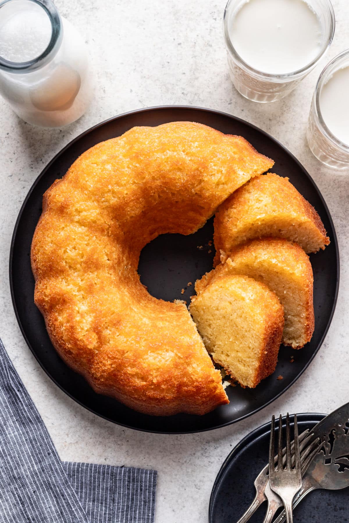 Kentucky butter cake on a black plate next to glasses of milk.
