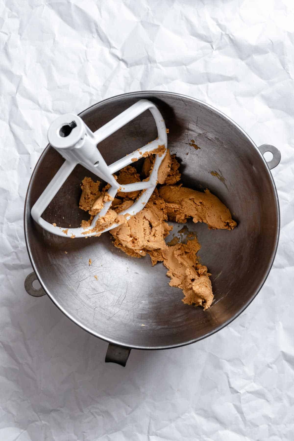 Peanut butter and powdered sugar beaten together in a silver mixing bowl.
