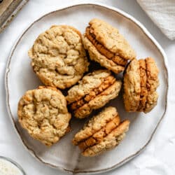 A white plate with 6 Do-si-dos cookies on it next to a cup of milk.