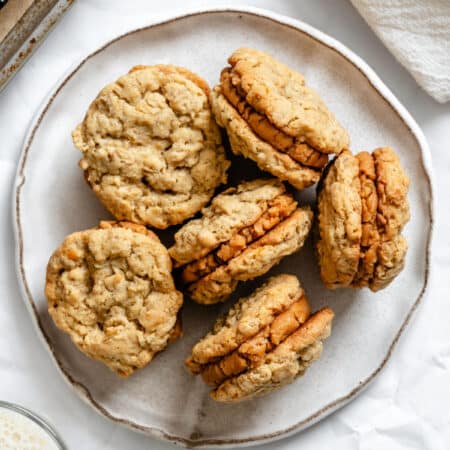 A white plate with 6 Do-si-dos cookies on it next to a cup of milk.