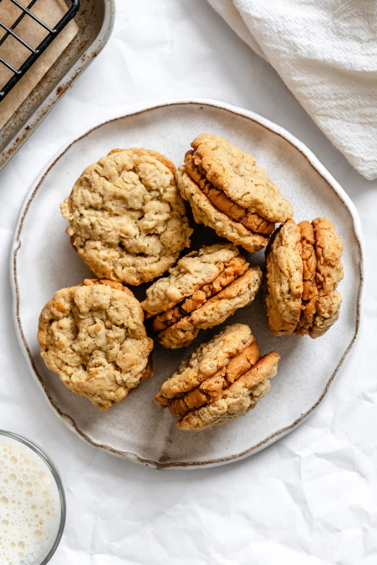 A white plate with 6 Do-si-dos cookies on it next to a cup of milk.