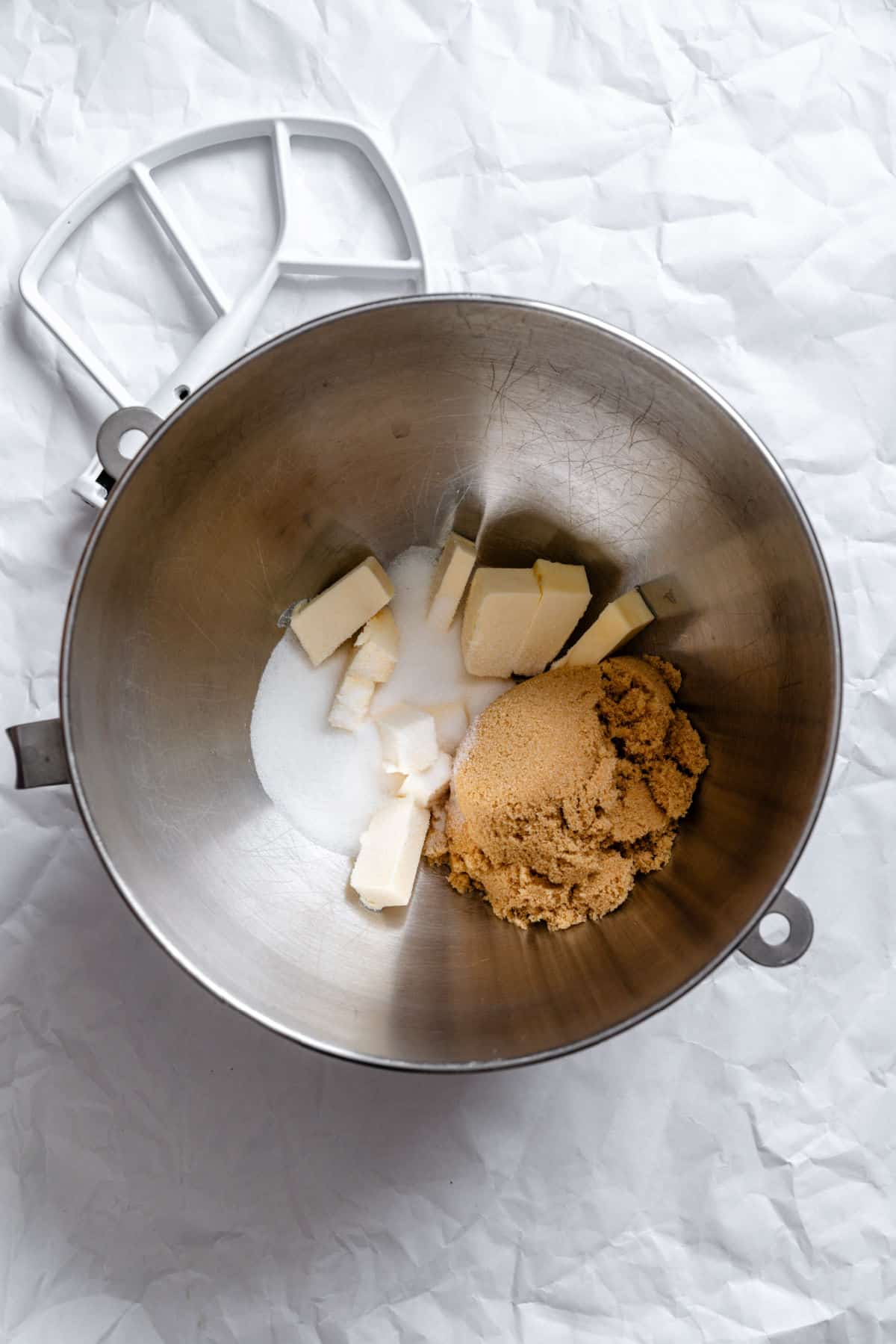 Butter and sugars in a silver mixing bowl.