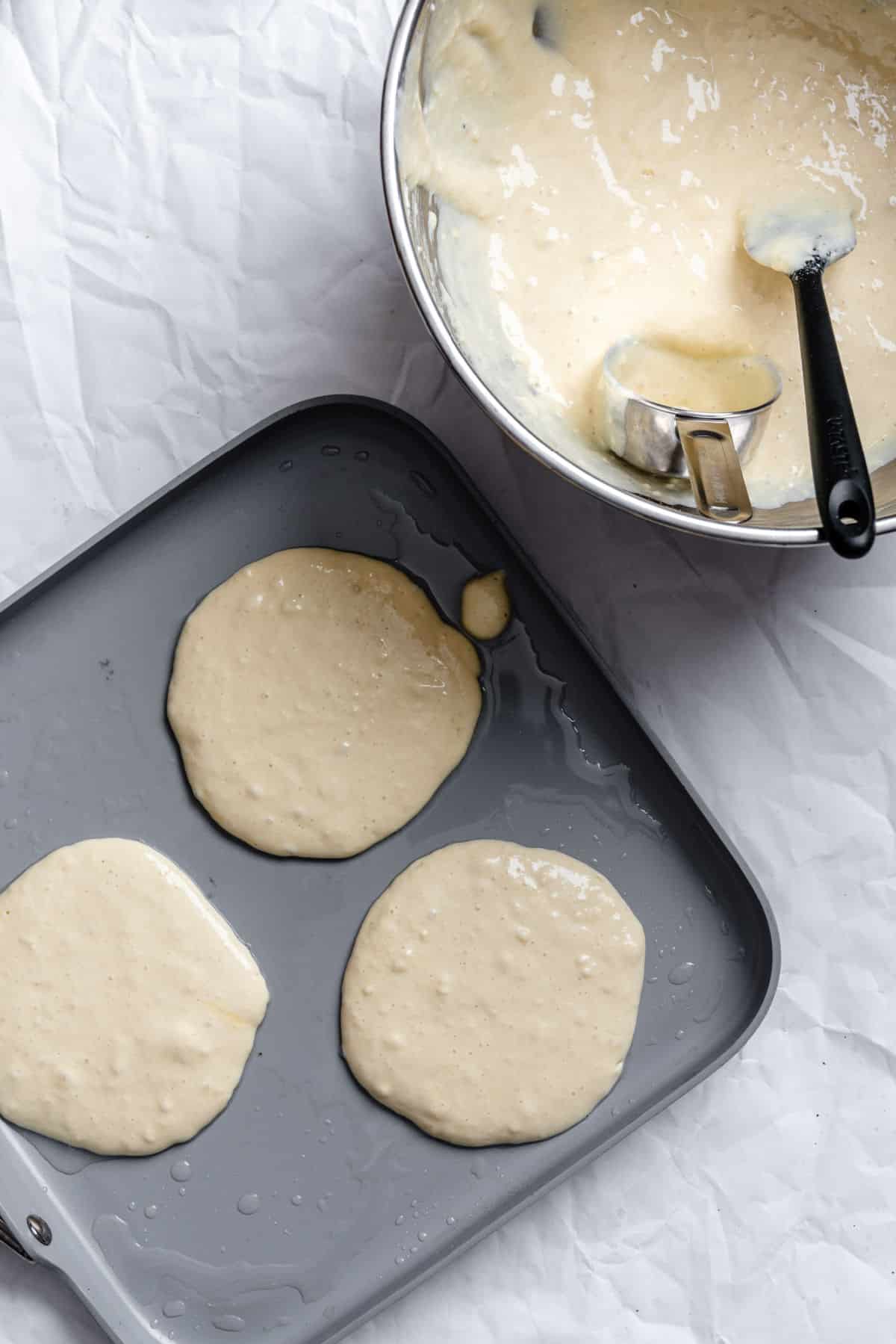 Pancakes cooking on a griddle pan.