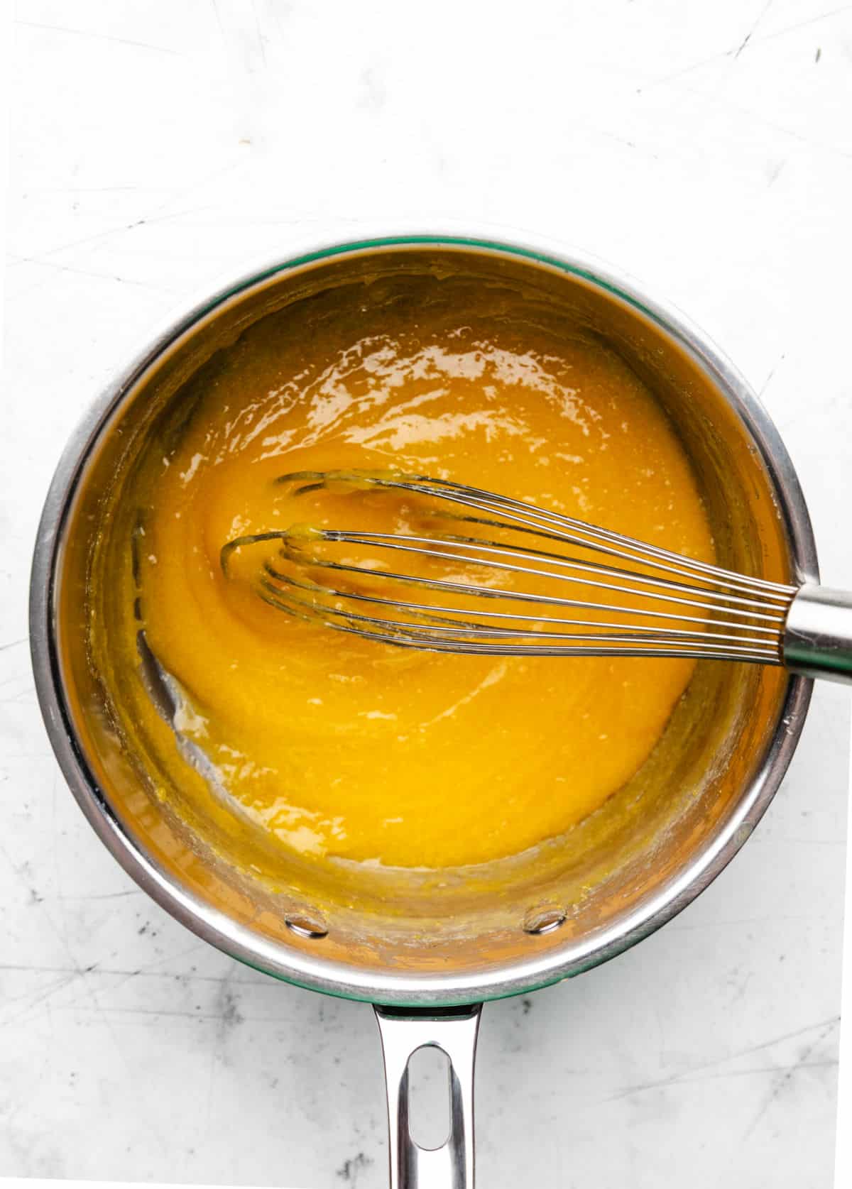 Thickened lemon curd in a saucepan.
