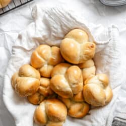 A basket of 60 minute dinner rolls next to a wire cooling rack with more rolls.